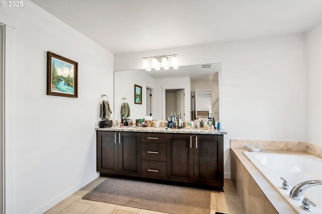 full bathroom featuring double vanity, a sink, tile patterned flooring, baseboards, and a bath