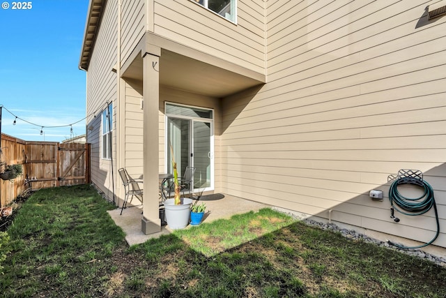 exterior space featuring a patio area, a gate, fence, and a yard