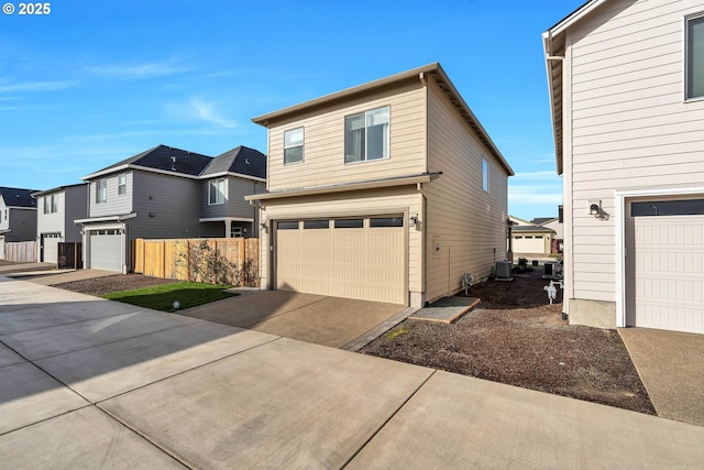 view of front of house with central AC, an attached garage, fence, and a residential view