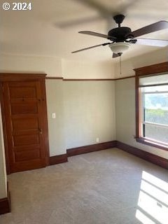 empty room with light colored carpet and ceiling fan