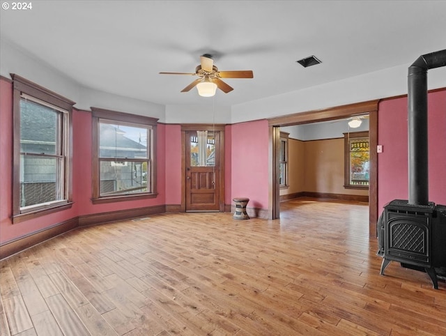 entrance foyer featuring a wood stove, ceiling fan, and light wood-type flooring