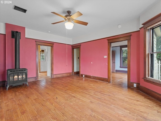 unfurnished living room featuring light hardwood / wood-style flooring, a wood stove, and ceiling fan