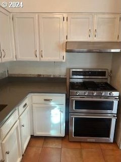 kitchen with white cabinets, light tile patterned flooring, and range with two ovens