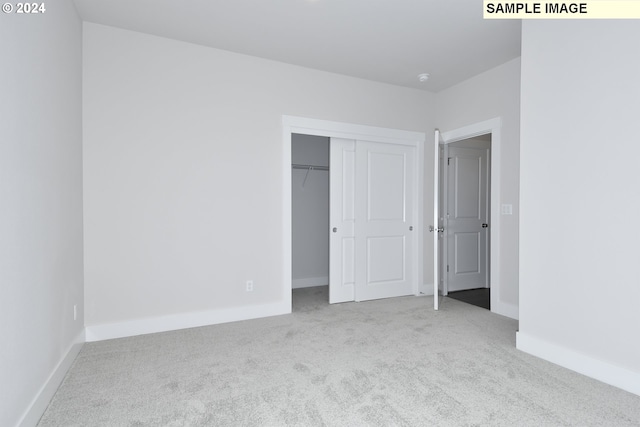 unfurnished bedroom with a closet and light colored carpet