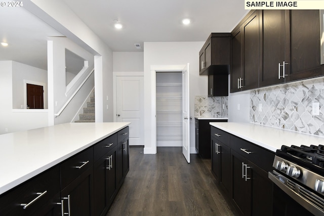 kitchen featuring dark brown cabinets, stainless steel range with gas stovetop, dark wood-type flooring, and backsplash