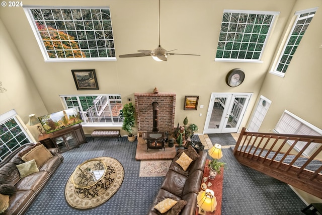 living room with french doors, carpet flooring, a wood stove, and a high ceiling