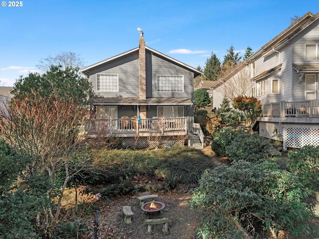 back of property featuring a wooden deck, a sunroom, and a fire pit