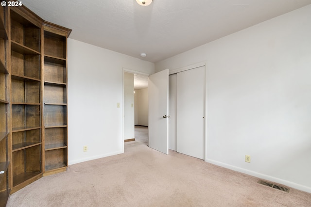 unfurnished bedroom featuring light carpet and a closet