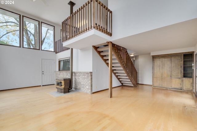 living room with a towering ceiling, a wood stove, and wood-type flooring