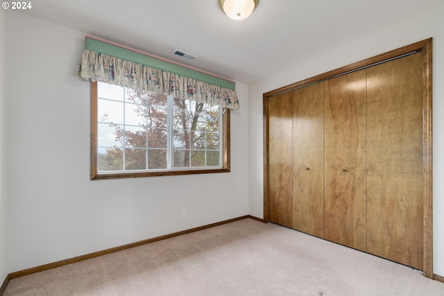 unfurnished bedroom featuring light carpet and a closet