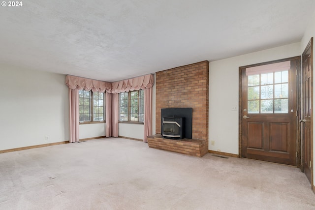 unfurnished living room with a wood stove, a textured ceiling, and light colored carpet