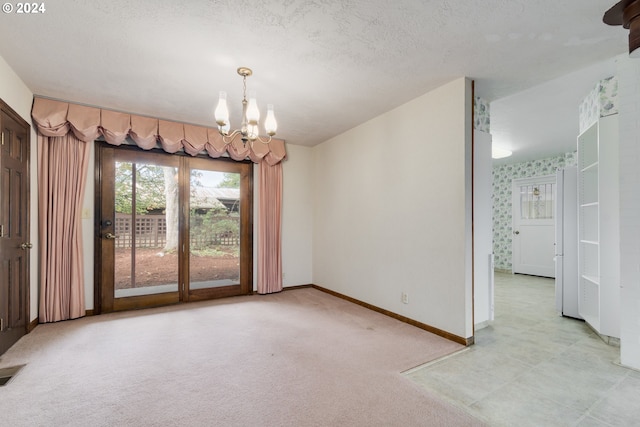 empty room featuring light carpet, a textured ceiling, and a chandelier