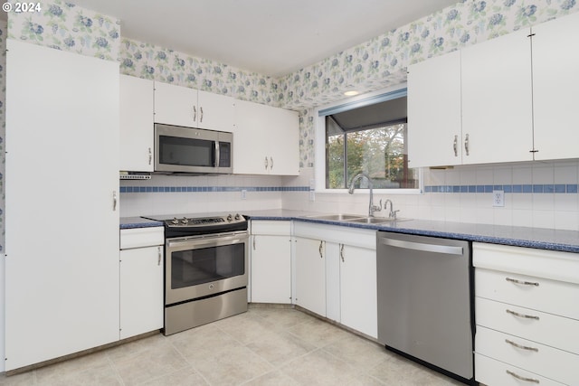 kitchen featuring sink, white cabinets, light tile patterned floors, appliances with stainless steel finishes, and tasteful backsplash