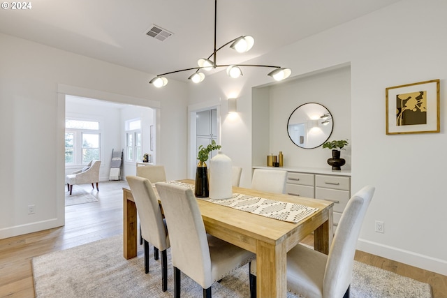 dining room with light hardwood / wood-style flooring and an inviting chandelier