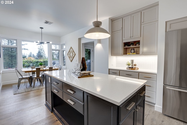 kitchen featuring gray cabinetry, stainless steel fridge, a center island, decorative backsplash, and light hardwood / wood-style flooring