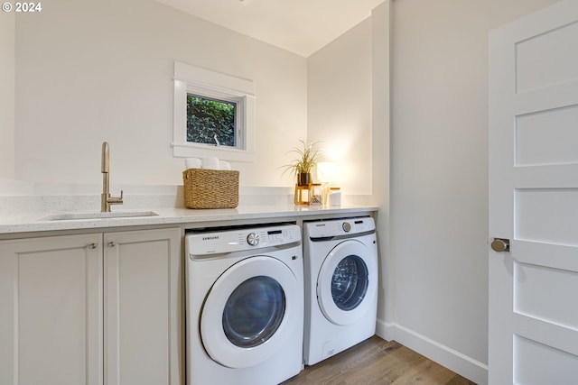 laundry area with cabinets, light hardwood / wood-style floors, washer and dryer, and sink