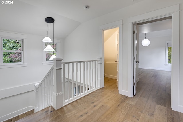 hallway featuring vaulted ceiling and light hardwood / wood-style flooring