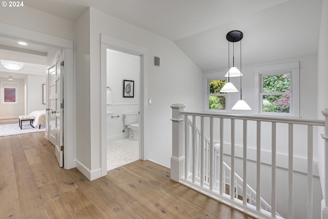 hallway with light wood-type flooring and lofted ceiling