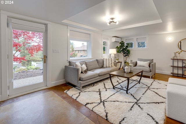 living room with a raised ceiling and a wall mounted air conditioner