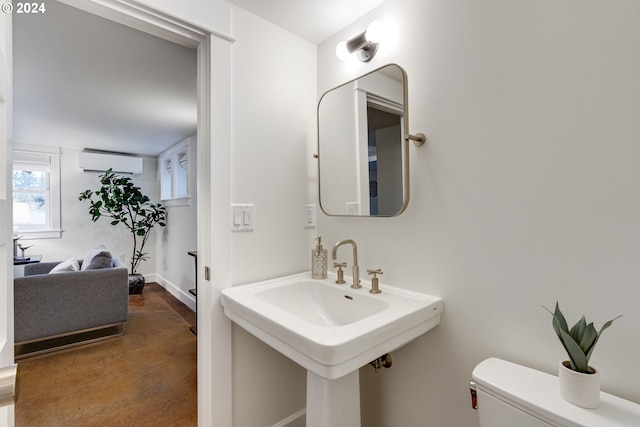 bathroom featuring concrete flooring, a wall mounted AC, and toilet