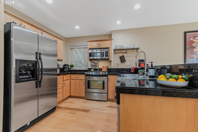 kitchen with dark countertops, light wood-type flooring, recessed lighting, stainless steel appliances, and a sink