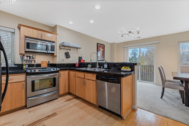 kitchen featuring tile countertops, light wood-style flooring, a peninsula, stainless steel appliances, and a sink