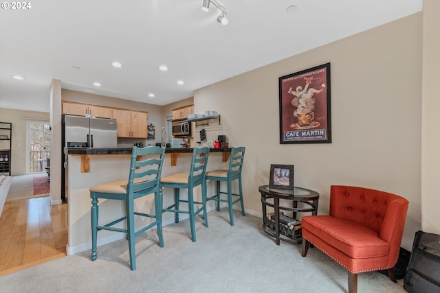 kitchen with a kitchen bar, a peninsula, dark countertops, and appliances with stainless steel finishes