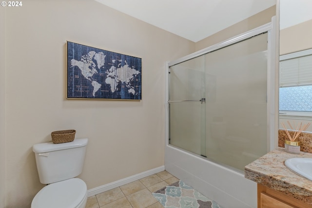 bathroom with baseboards, enclosed tub / shower combo, a sink, tile patterned floors, and toilet