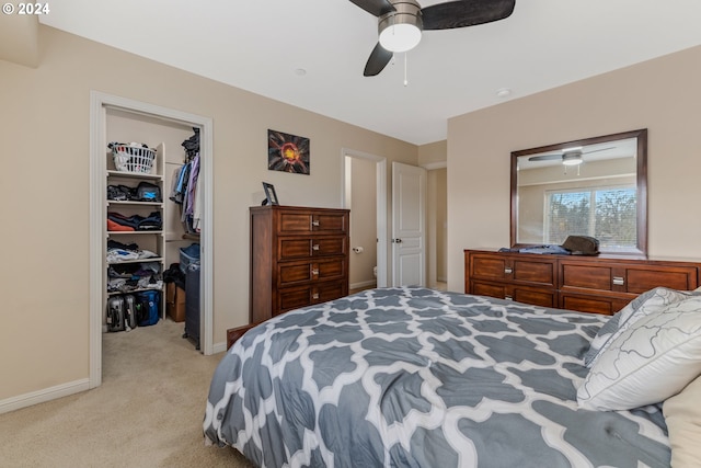 bedroom with baseboards, a walk in closet, light carpet, and a closet