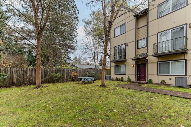 view of yard featuring central AC and fence