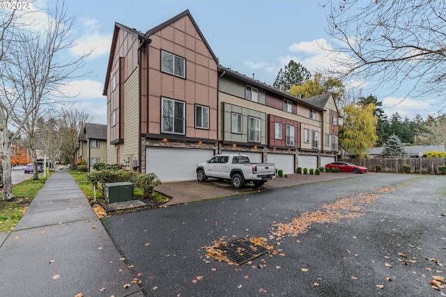 view of front facade with aphalt driveway, fence, and a garage