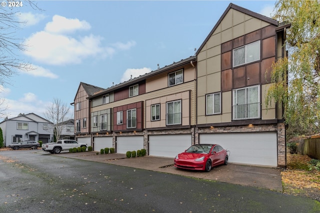 view of front of home with stucco siding, aphalt driveway, stone siding, a residential view, and a garage