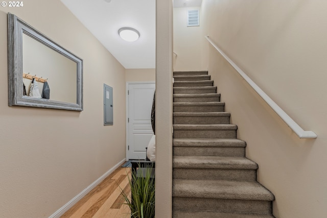 stairs with wood-type flooring and electric panel