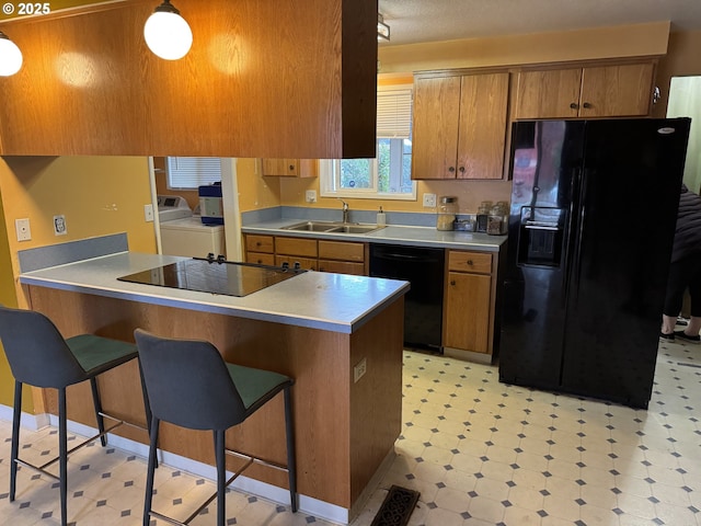 kitchen with washer and dryer, black appliances, a breakfast bar, sink, and a textured ceiling