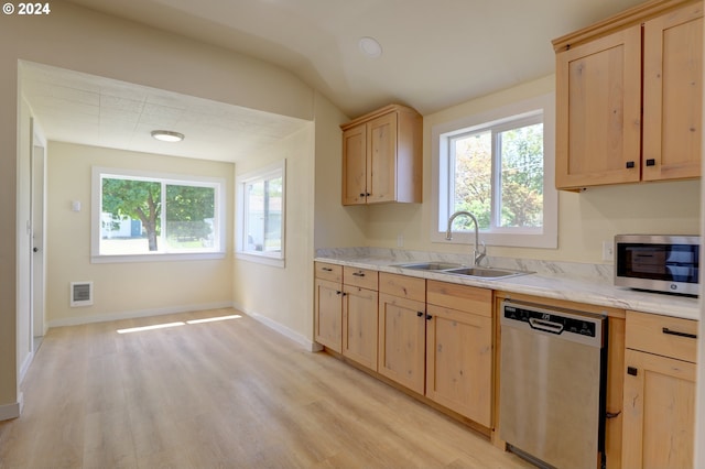 kitchen featuring light stone countertops, light brown cabinetry, appliances with stainless steel finishes, sink, and light hardwood / wood-style floors