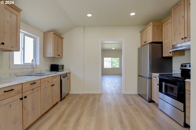 kitchen with appliances with stainless steel finishes, light brown cabinetry, sink, and light wood-type flooring