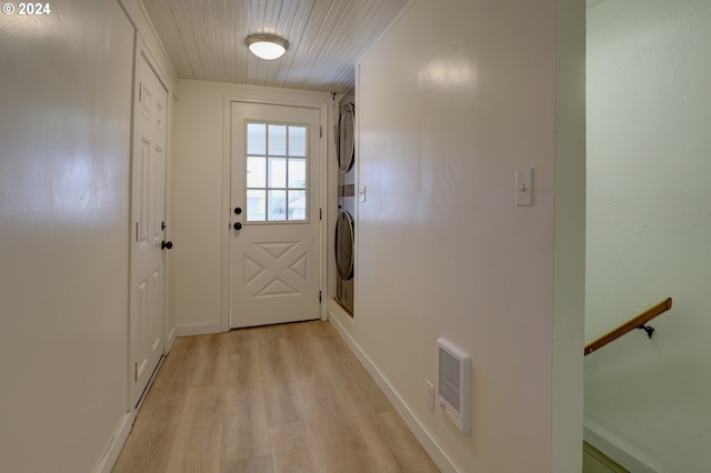 entryway featuring ornamental molding, light wood-type flooring, and stacked washer and dryer