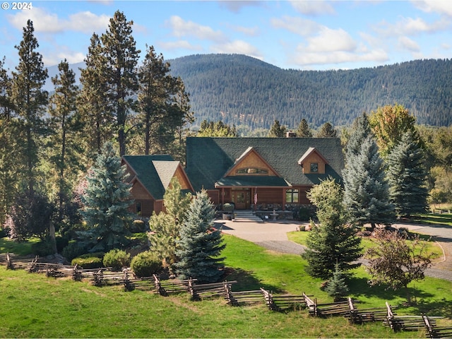 back of house with fence, a mountain view, and a view of trees