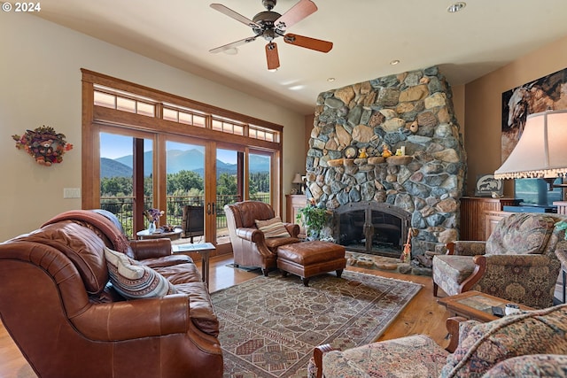 living room featuring a fireplace, a mountain view, ceiling fan, french doors, and light hardwood / wood-style flooring