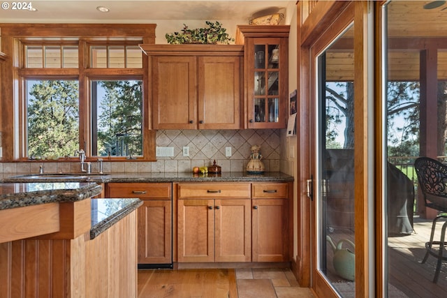 kitchen featuring dark stone countertops, light hardwood / wood-style floors, backsplash, and sink