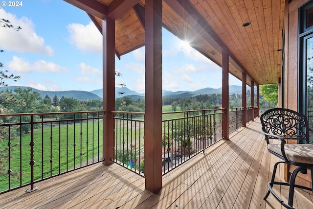 wooden deck with a lawn and a mountain view