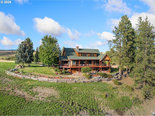 back of property with a lawn, a deck, and a rural view