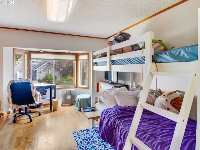 bedroom featuring wood-type flooring, a textured ceiling, and ornamental molding