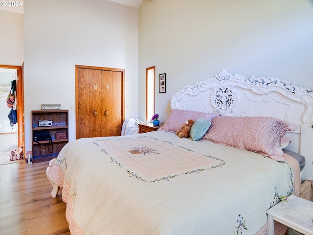 bedroom featuring hardwood / wood-style flooring and a high ceiling