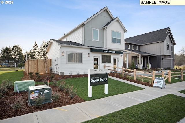 view of front of home featuring board and batten siding, a front yard, and fence