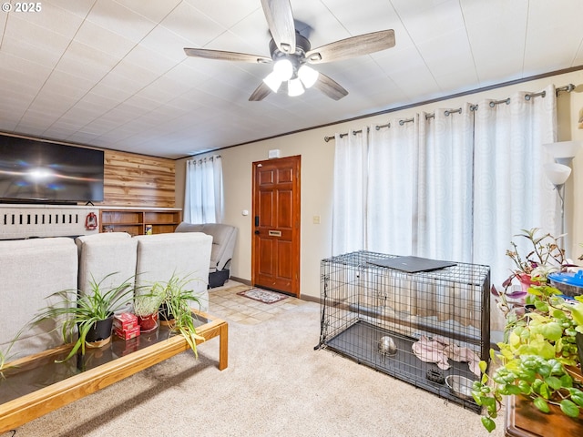 carpeted living room with ceiling fan and wooden walls