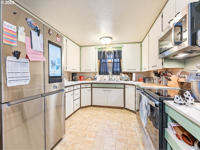 kitchen with appliances with stainless steel finishes, backsplash, a textured ceiling, sink, and white cabinets