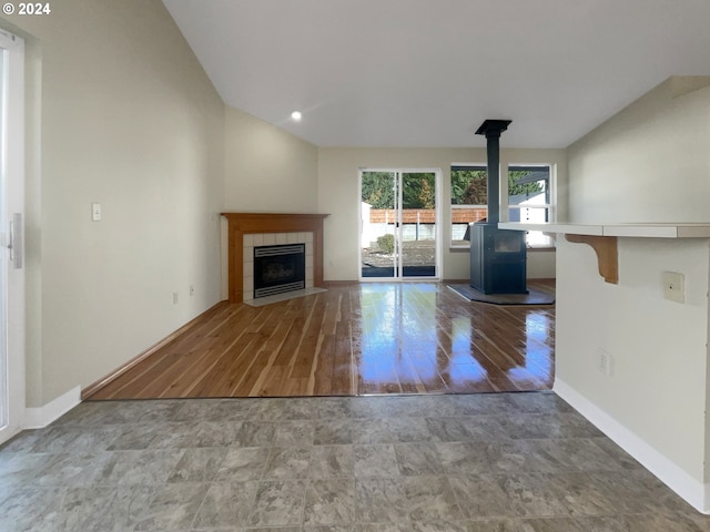 unfurnished living room with lofted ceiling, hardwood / wood-style flooring, and a wood stove