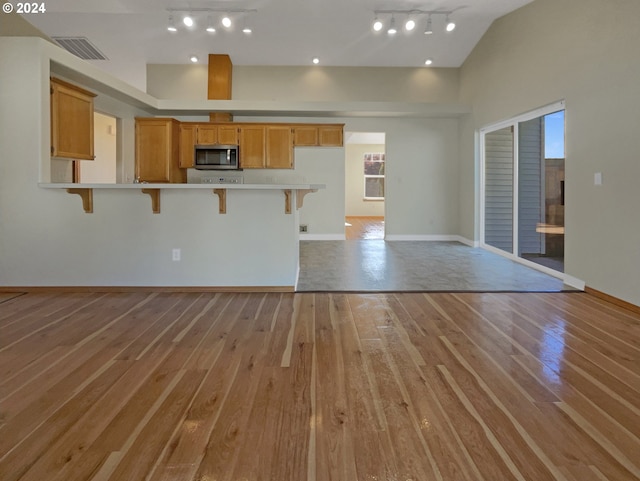 kitchen with track lighting, light hardwood / wood-style floors, and a kitchen bar