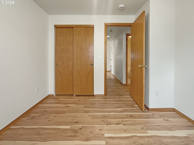 unfurnished bedroom featuring light wood-type flooring and a closet